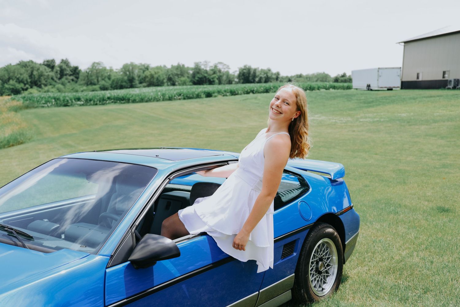 A bright blue sports car parked in a grassy field on a sunny day.
