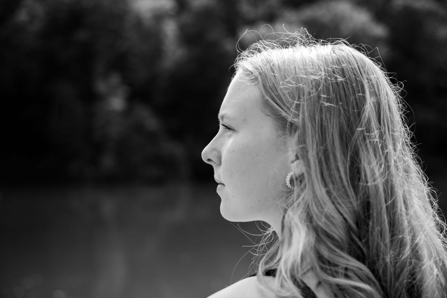 Side profile portrait with sunlit hair against a dark background.
