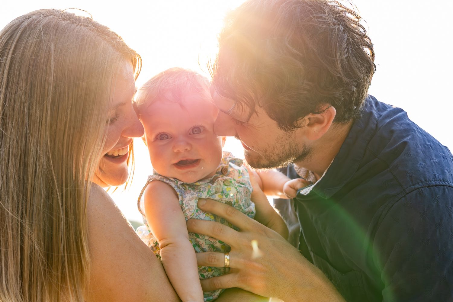 Four sequential photos show a tender moment between parent and baby silhouetted against bright sunlight.