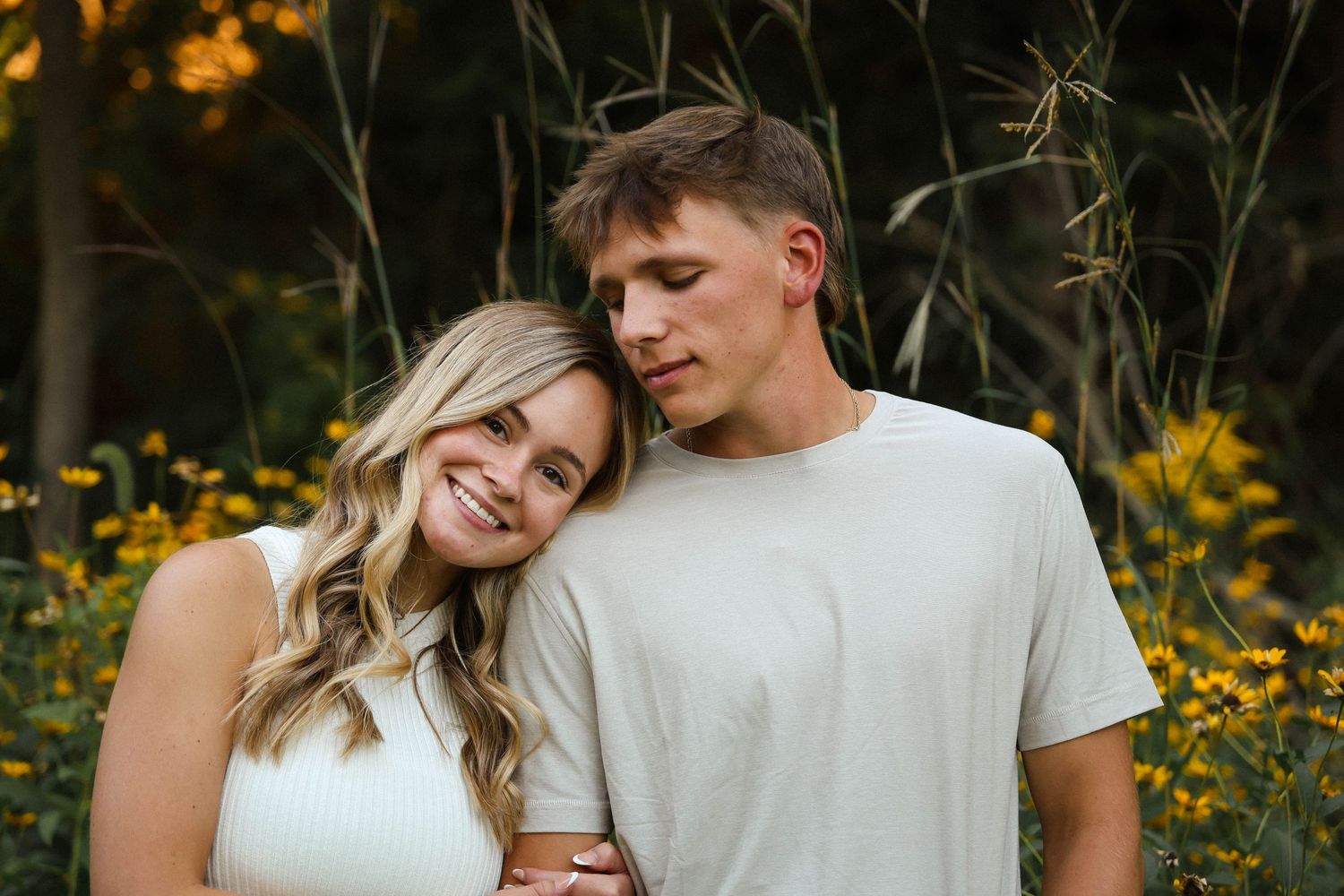 Romantic couple portrait in a field of yellow wildflowers at sunset.