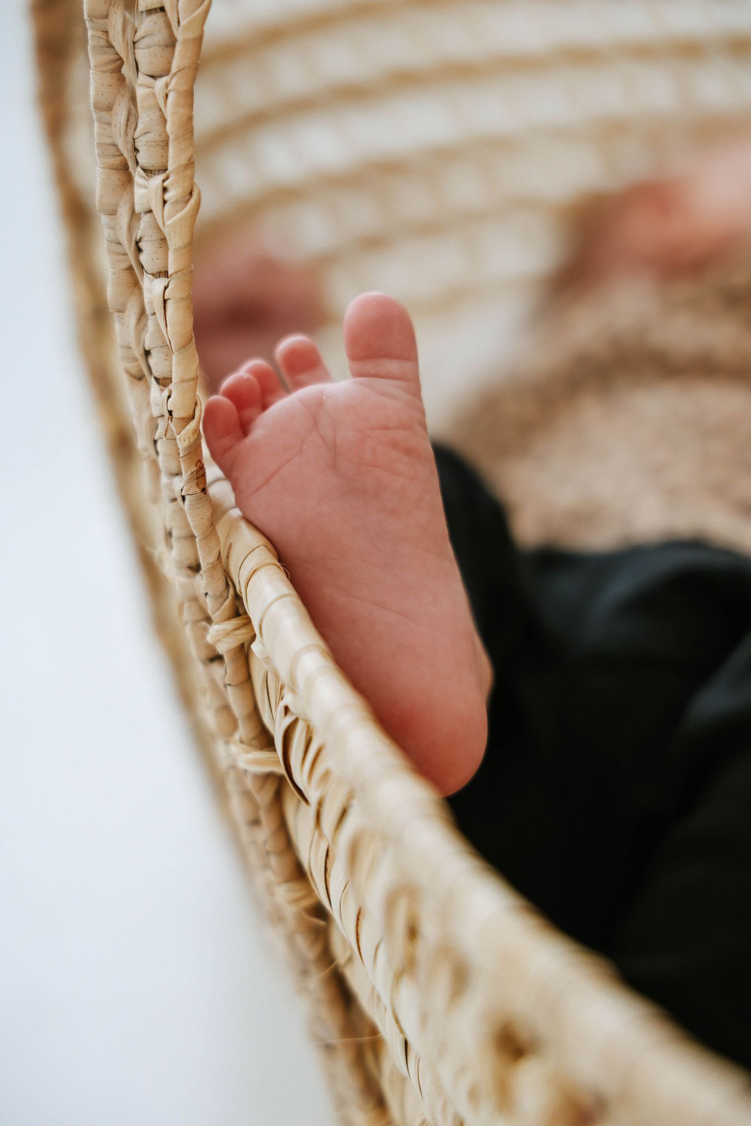 Close-up of baby's foot resting against woven basket edge.
