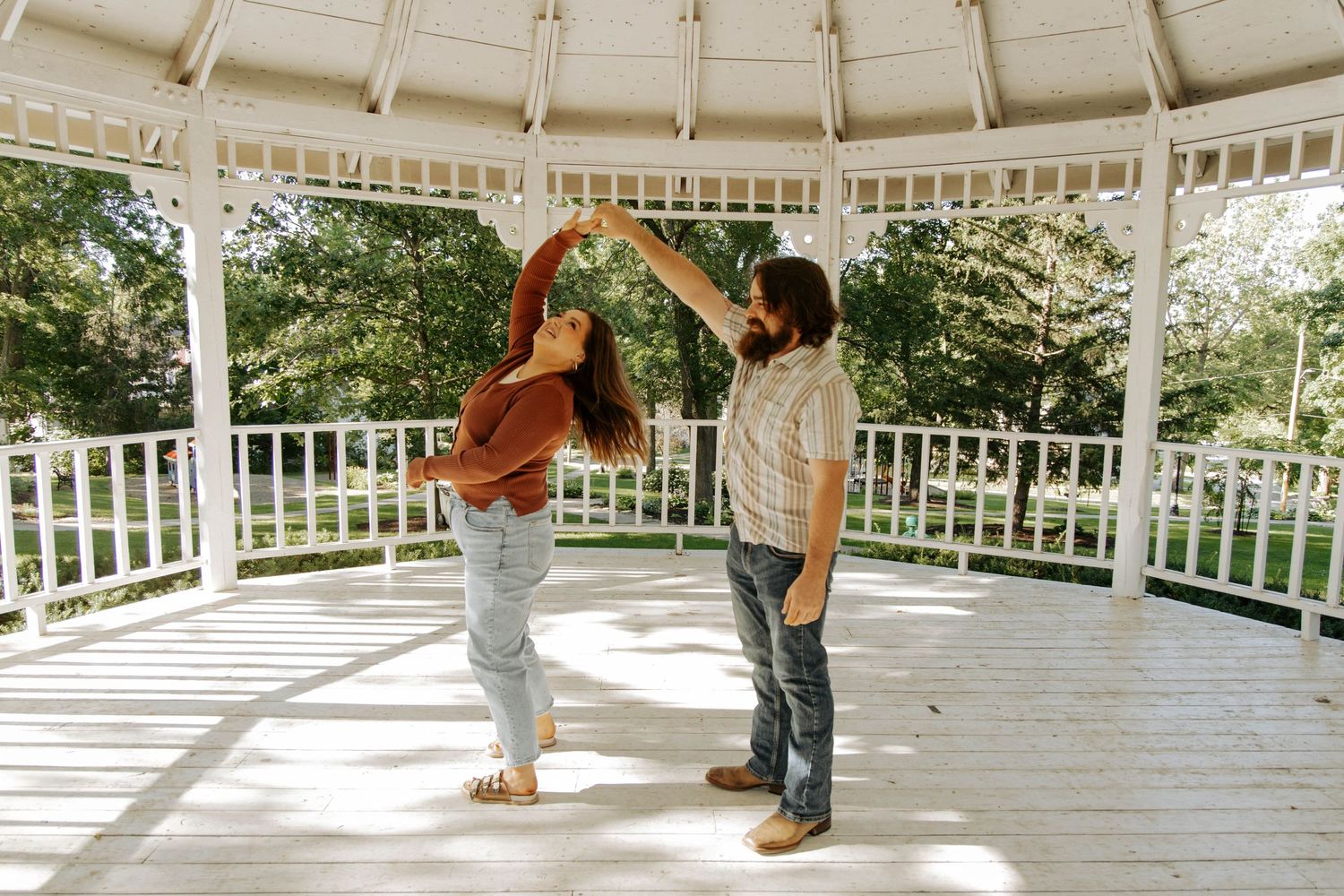 Two people dancing together in a white gazebo on a sunny day.