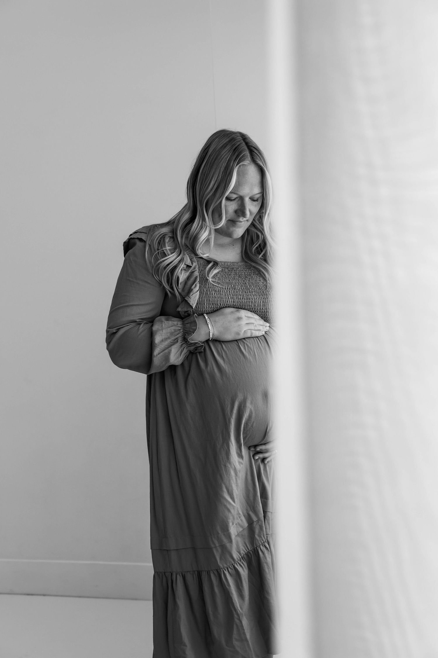 Candid black and white portrait of an expectant mother in a flowing maxi dress.