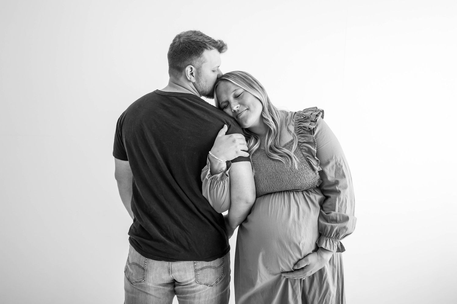 Intimate black and white portrait of an expecting couple embracing.