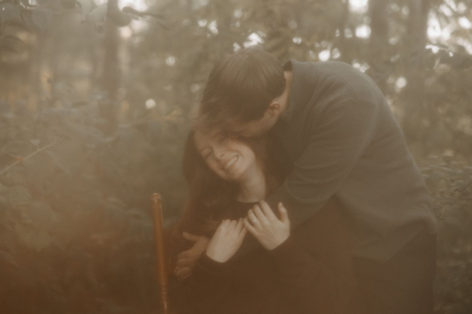 A person holds a small white butterfly on their finger in a dreamy forest setting with soft natural lighting.