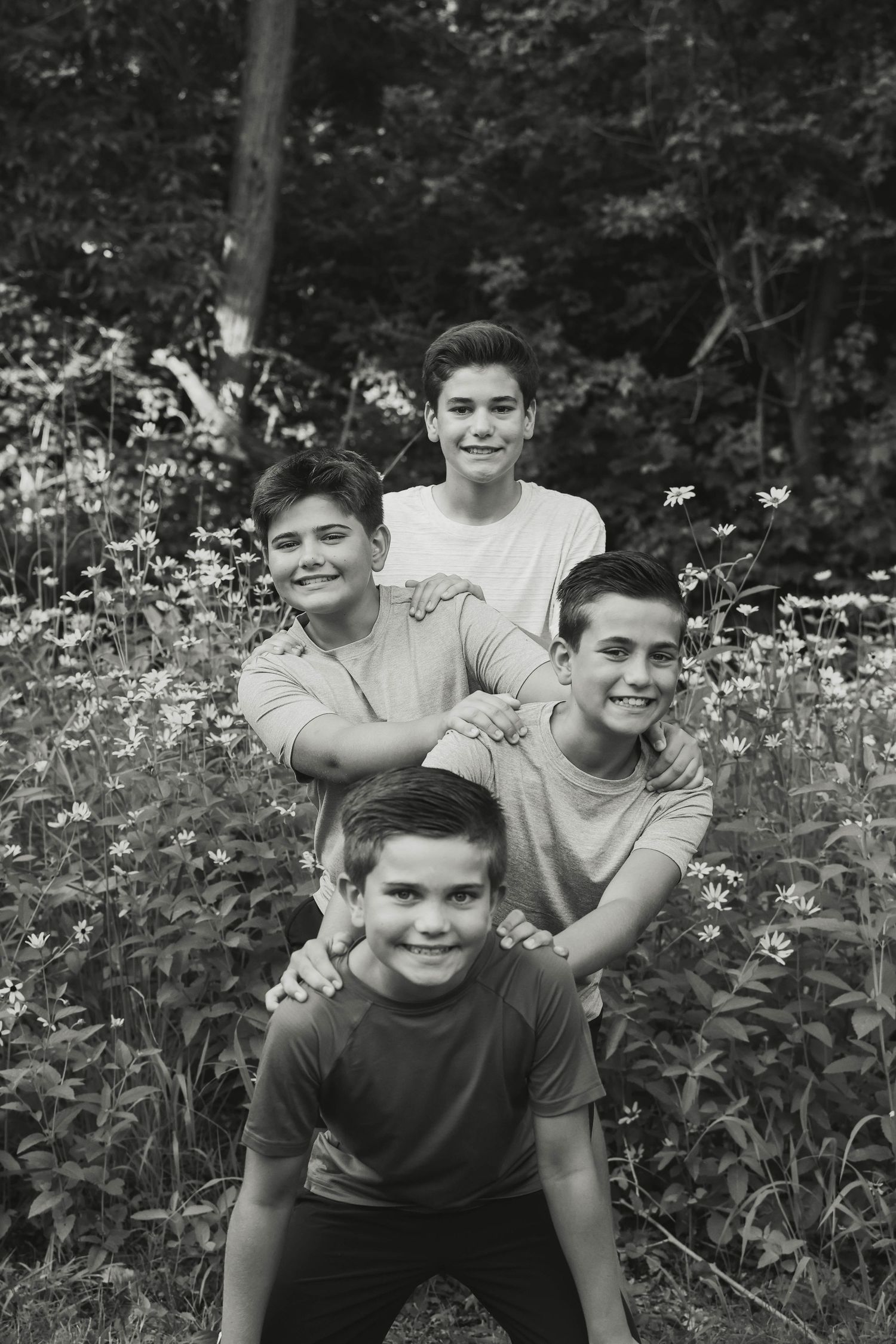 Four young boys posing playfully together in a wildflower meadow.