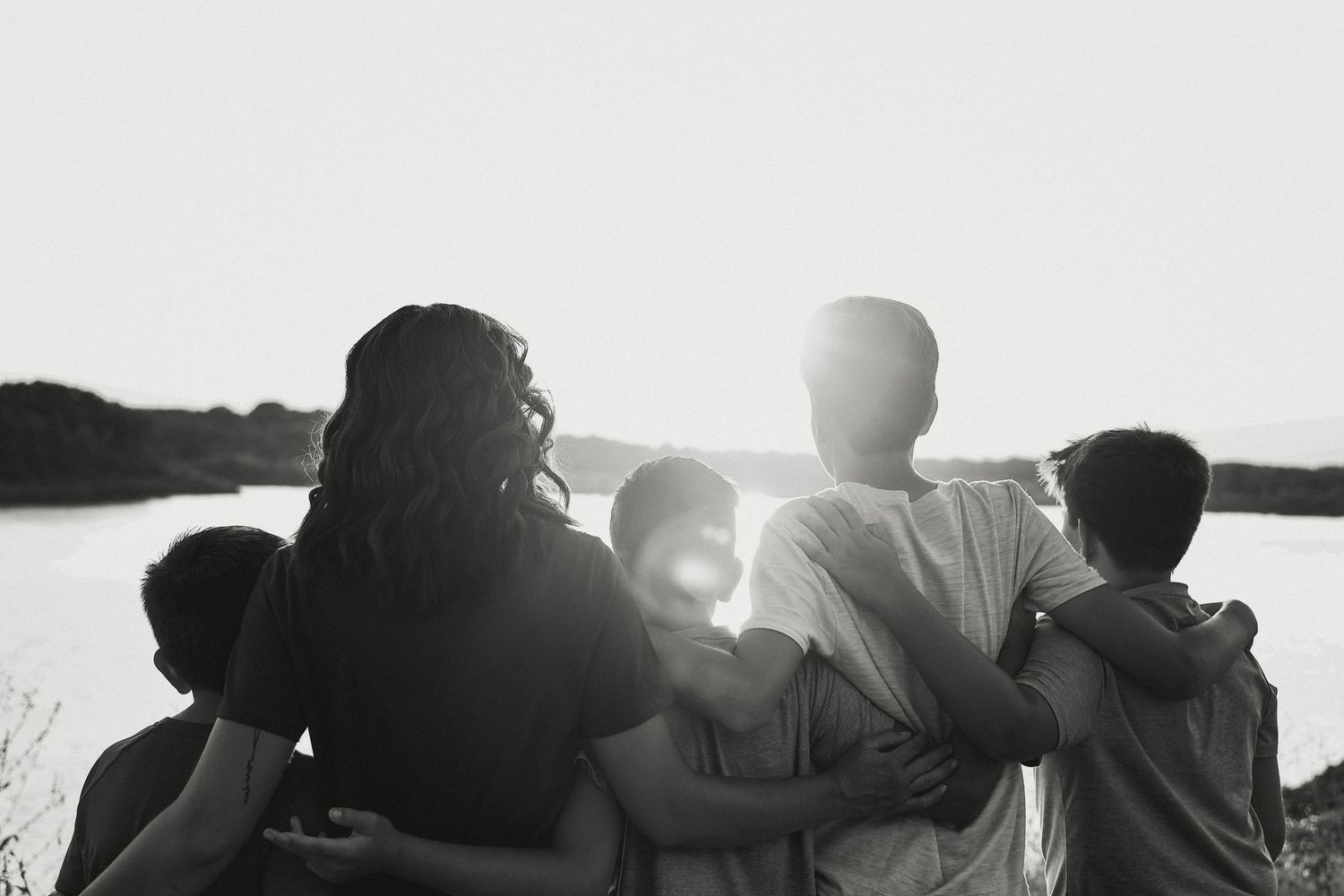 Silhouette of a family sitting together by a lake at sunset.
