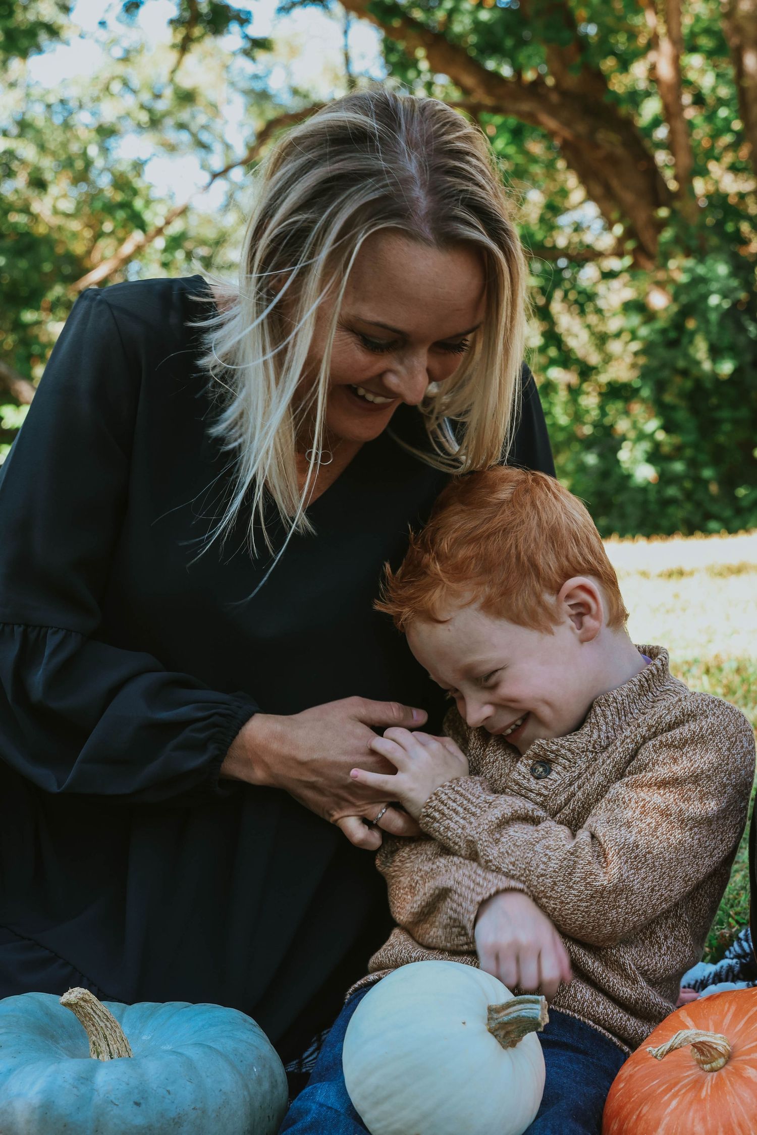 Candid moment of playful interaction with pumpkins during fall photo session.