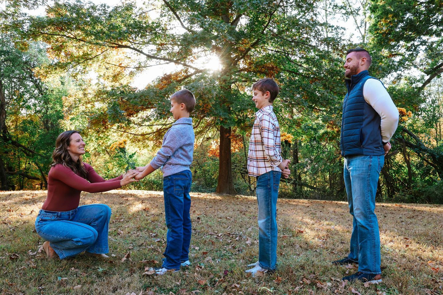 Family gathering in golden sunlight beneath trees having a meaningful interaction.
