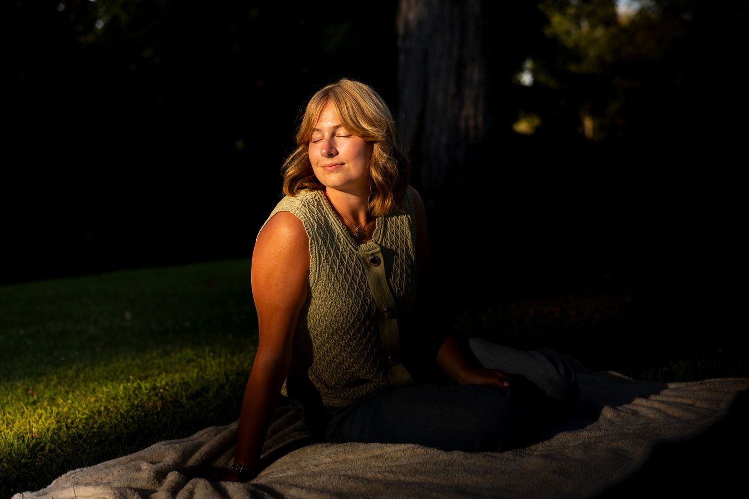 Artistic sunset photoshoot featuring a green sleeveless top against a dark natural backdrop.