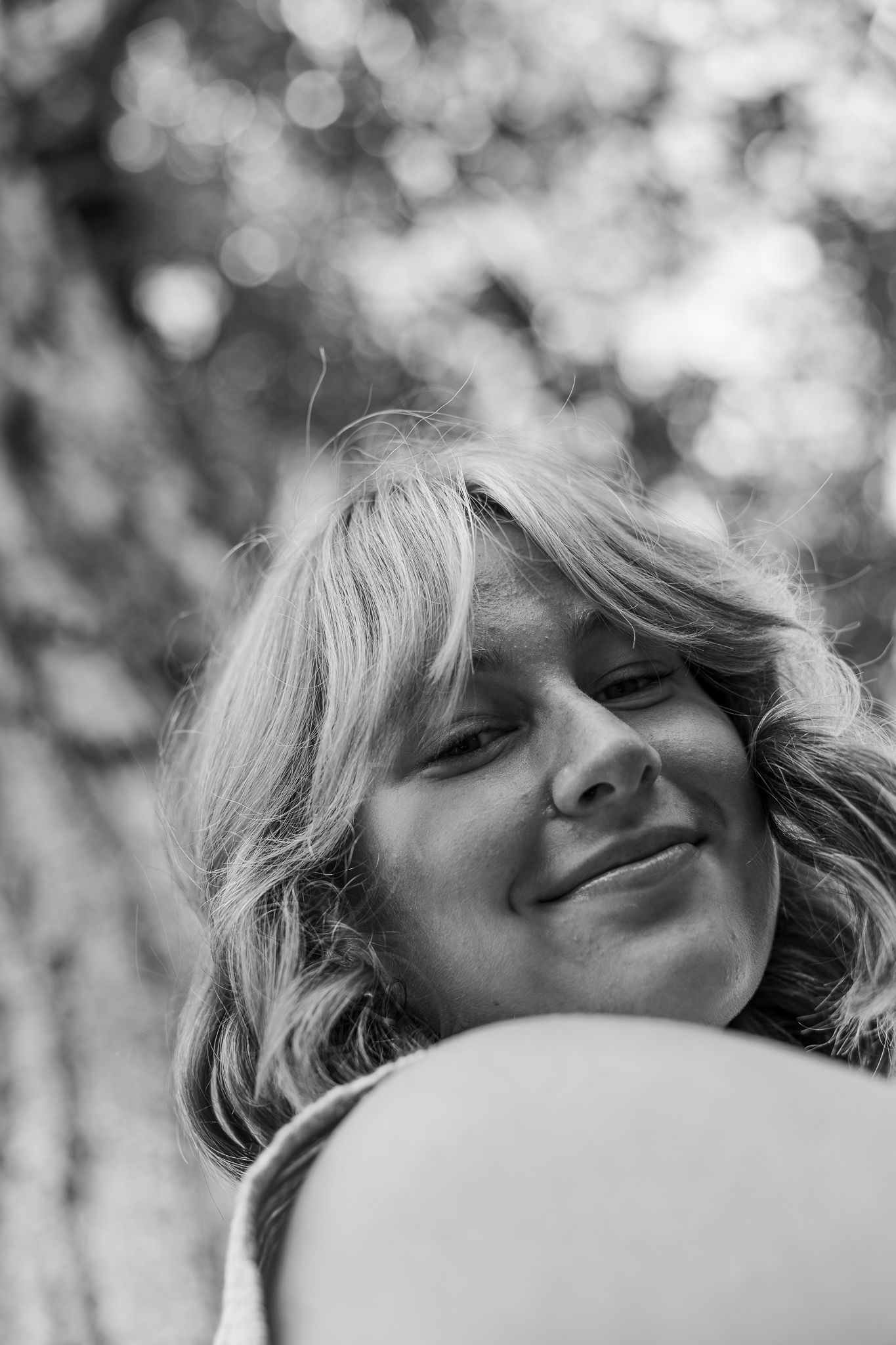 A series of black and white portraits showing joyful expressions with natural bokeh background.