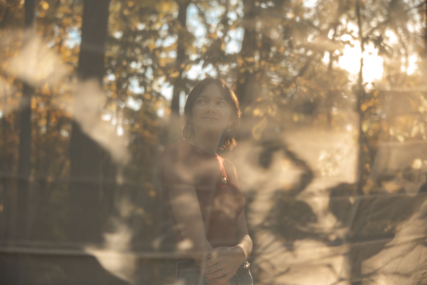 Silhouettes of people walking through a park during golden hour with sunlight filtering through trees.