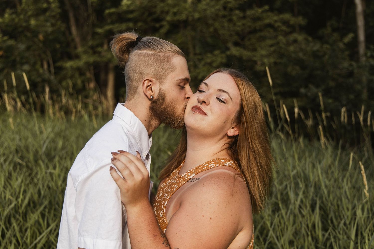 A romantic couple embracing in tall grass during golden hour.