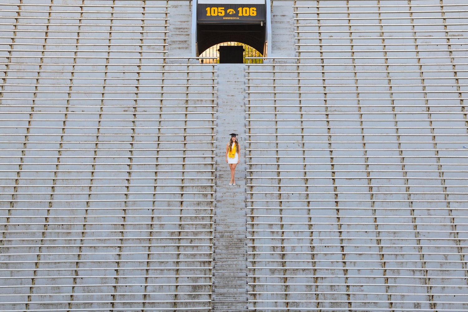 An aerial view shows a lone person walking up Kinnick Stadium bleachers beneath a yellow sign marked 105-108.