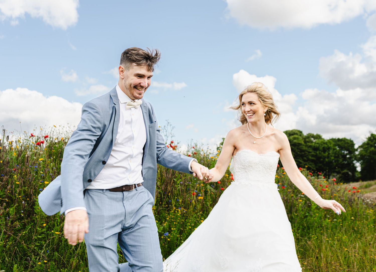 Joyful wedding couple dancing together in a meadow of wildflowers on their special day.