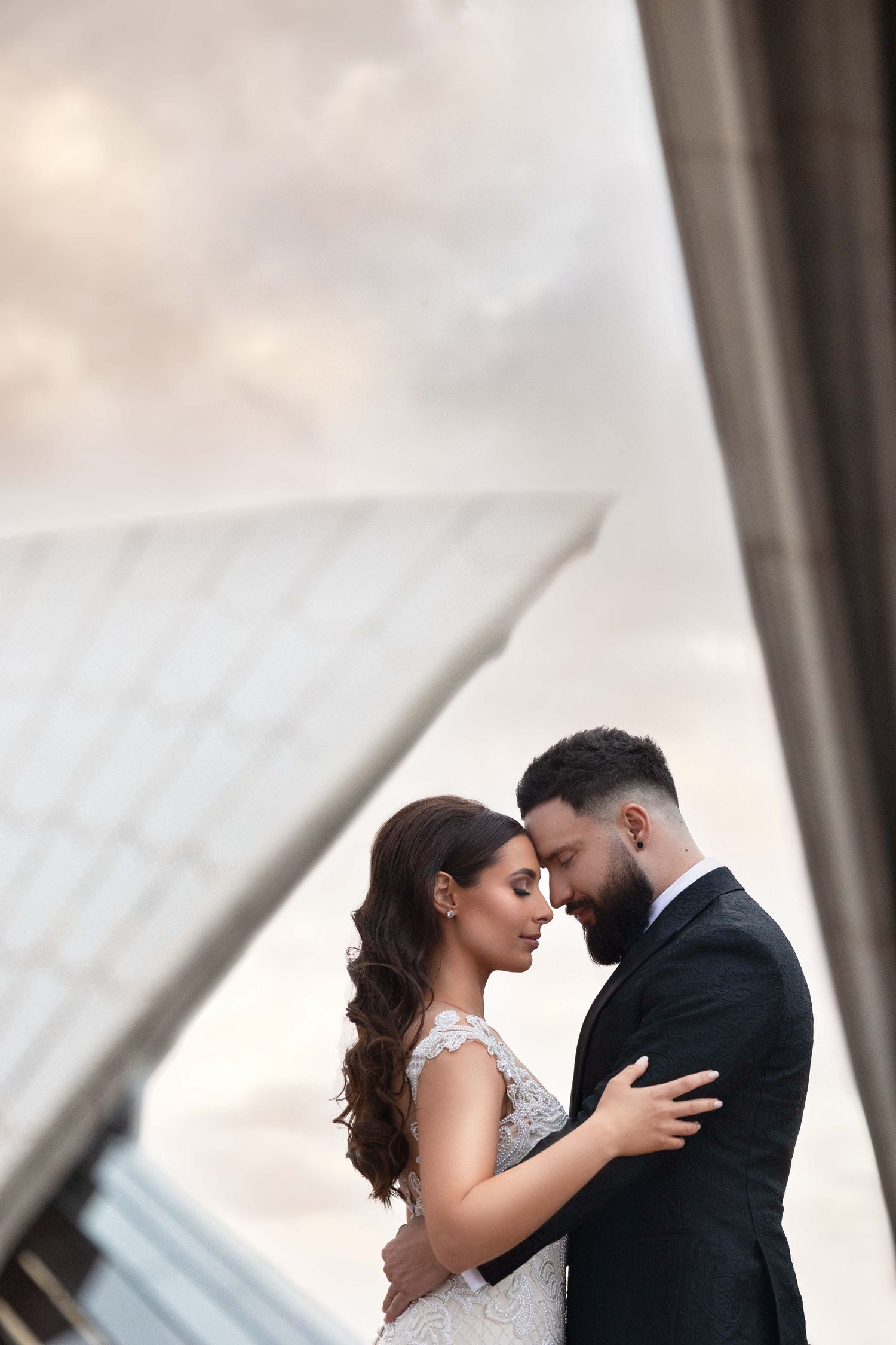 Bride and groom share an intimate moment in front of the Sydney Opera House at sunset.