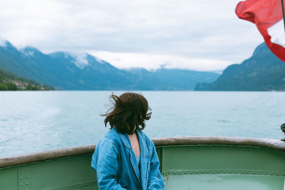 View from a boat showing turquoise waters and misty mountains with a red flag waving in the breeze.