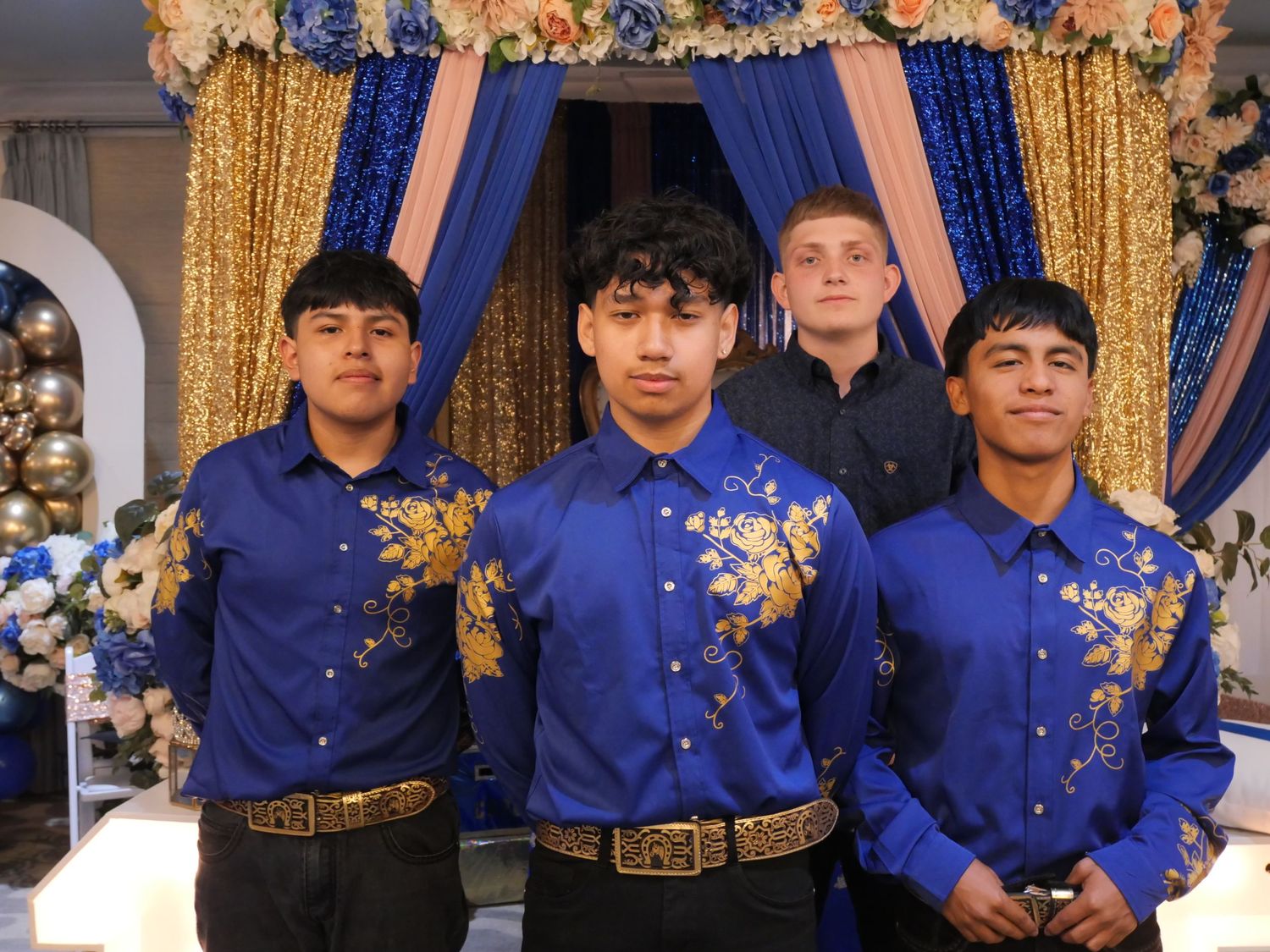 Group photo of young men in matching royal blue shirts with gold floral decorations.
