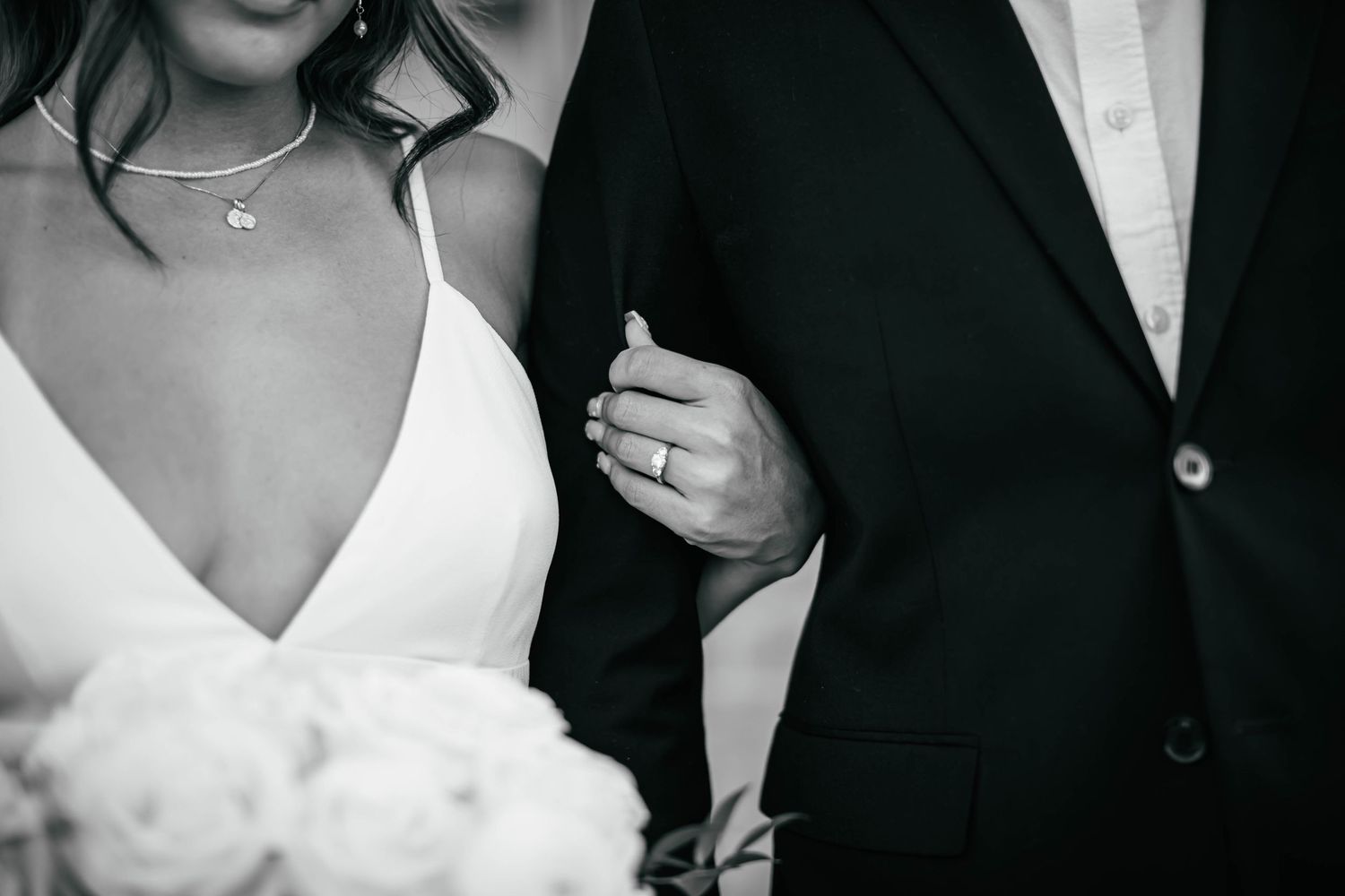 Close-up black and white details of formal wedding attire and jewelry.