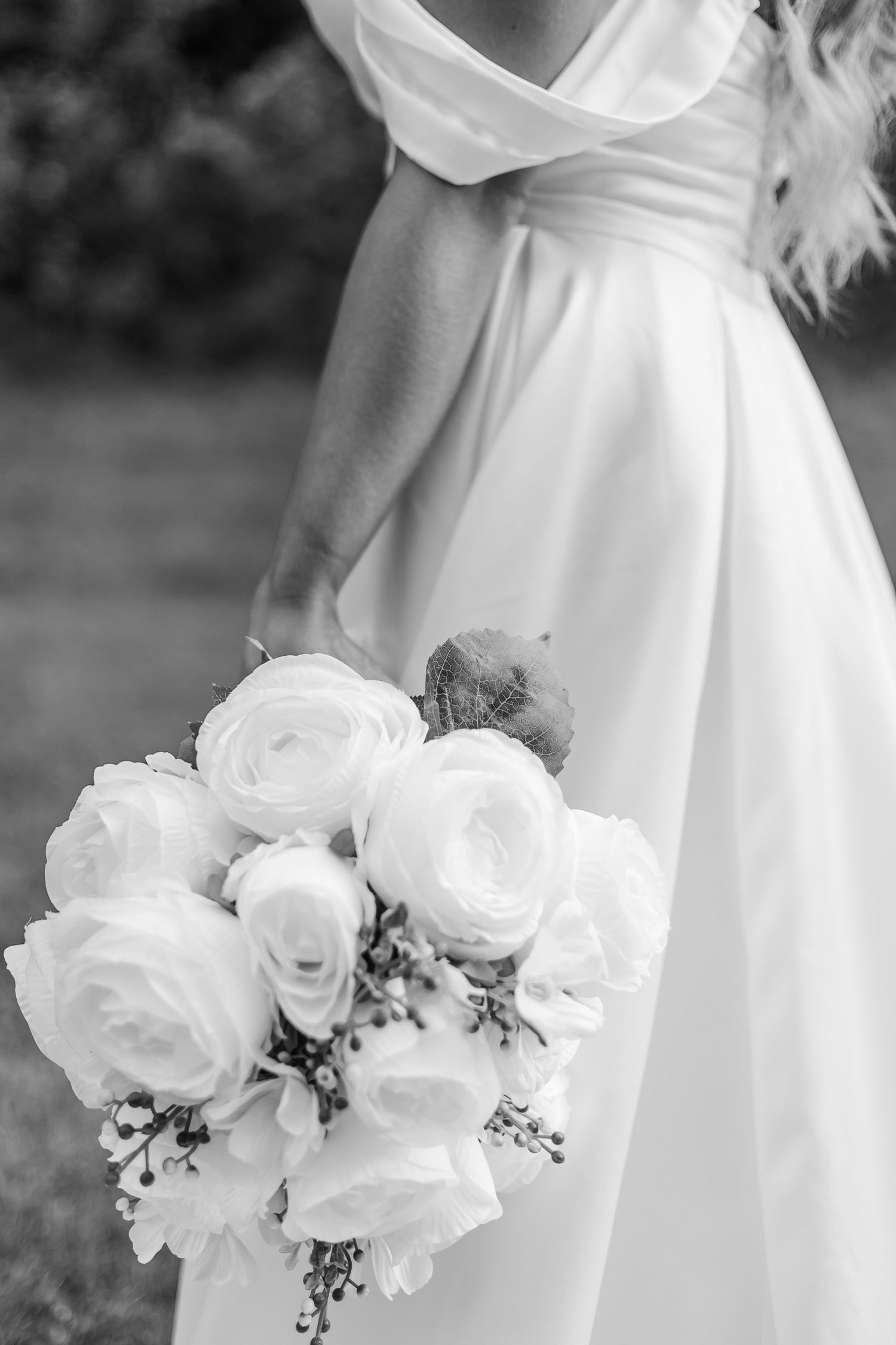 Detailed shot of white rose wedding bouquet with delicate greenery accents.