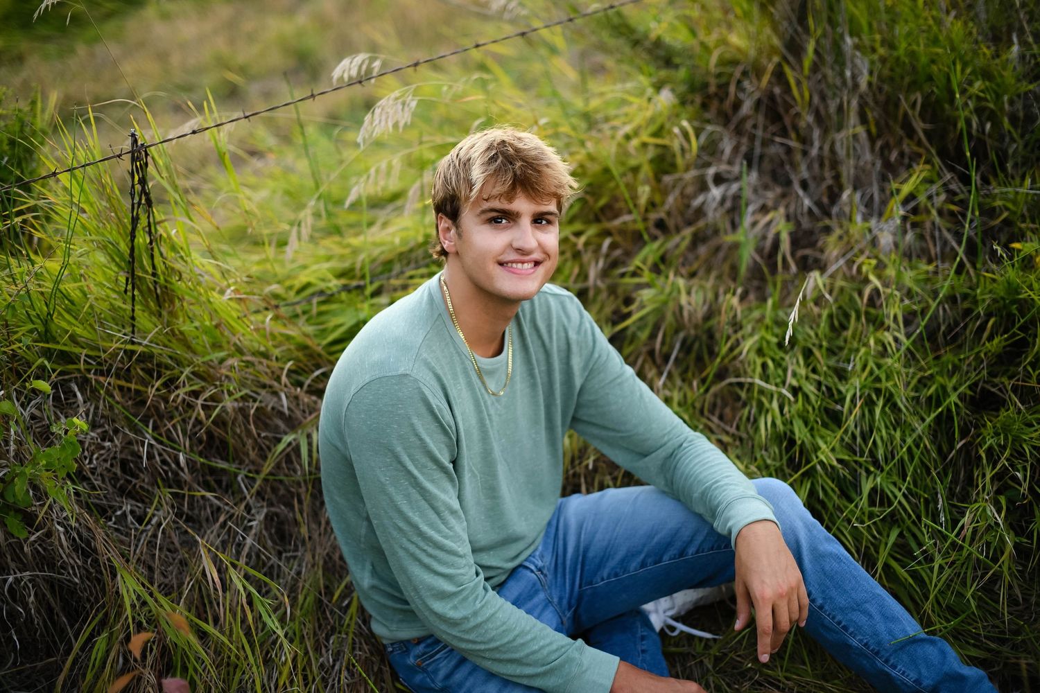 high school boy in green shirt sitting in a field