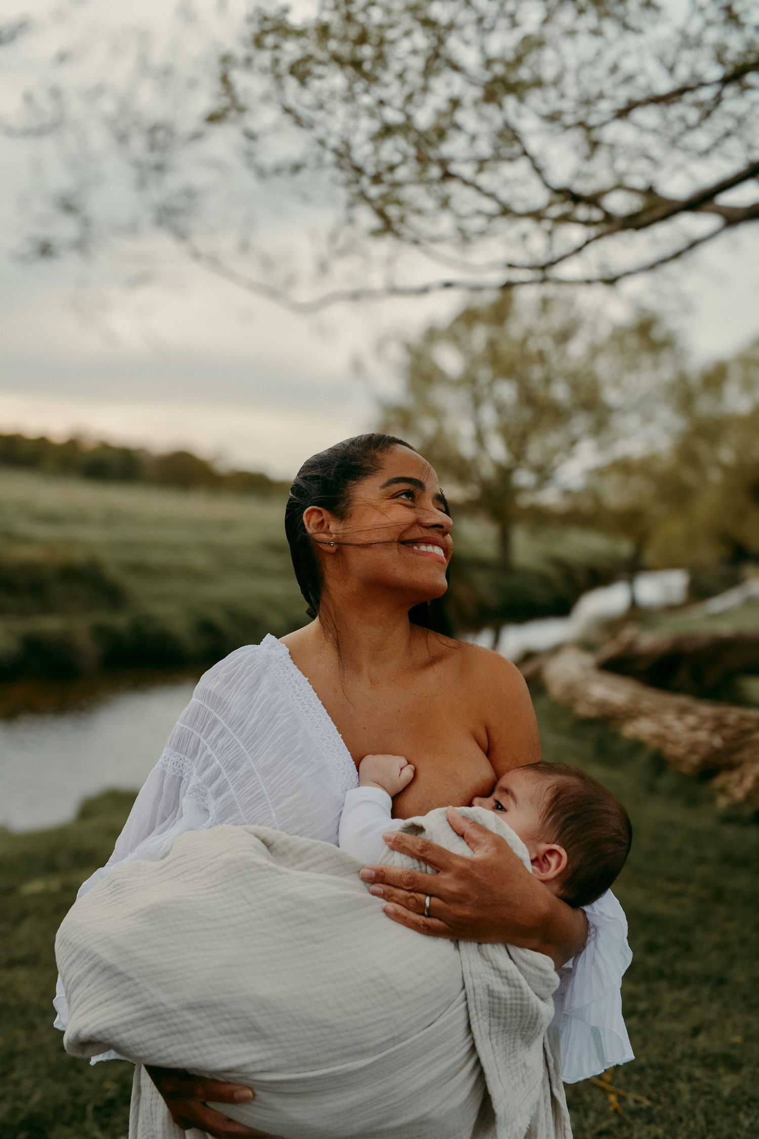 A candid moment captured outdoors showing nurturing care beside a flowing stream at dusk.