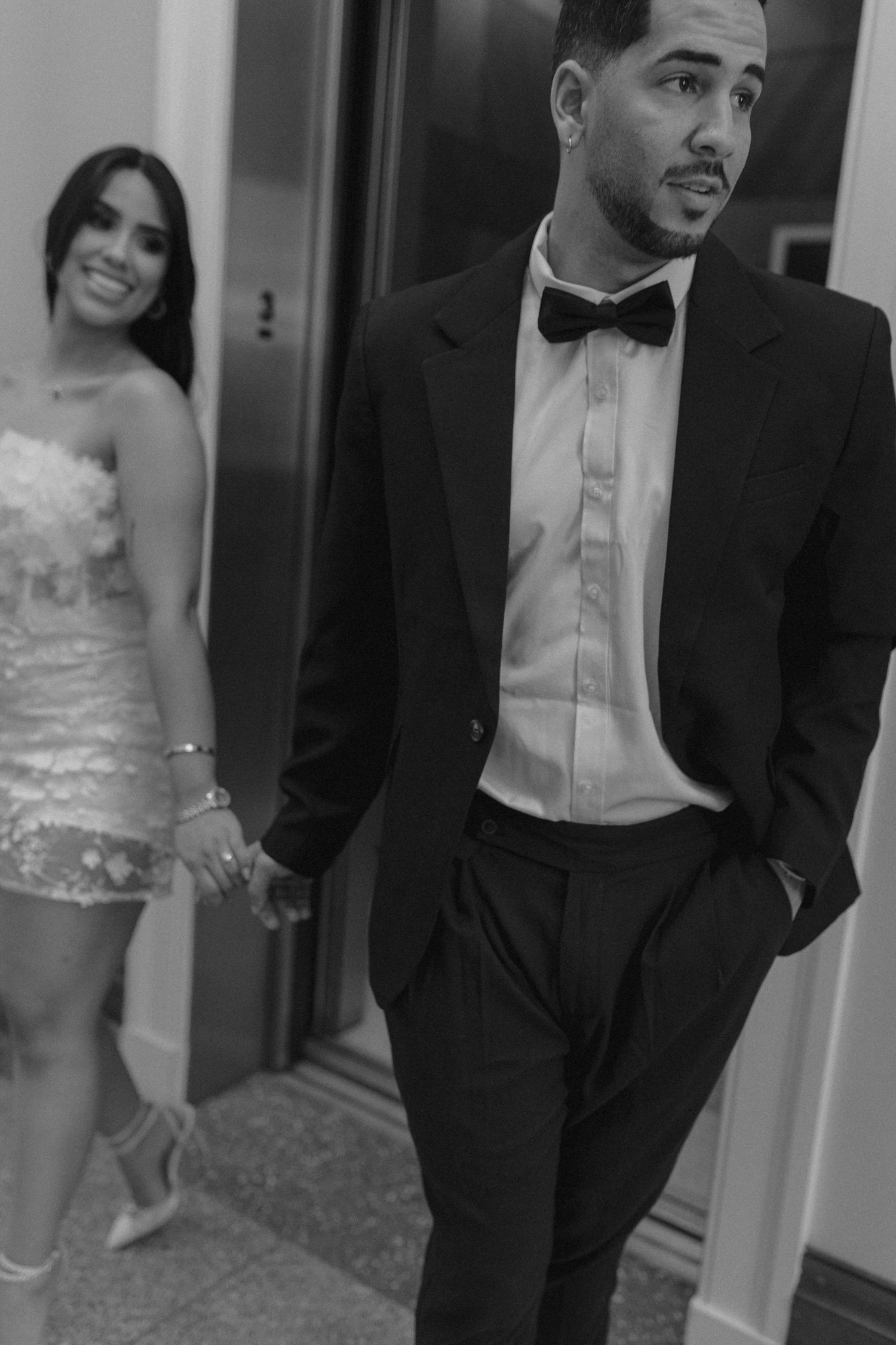 Black and white photo of a couple in formal attire, with her in a sparkly dress and him in a tuxedo with bow tie.