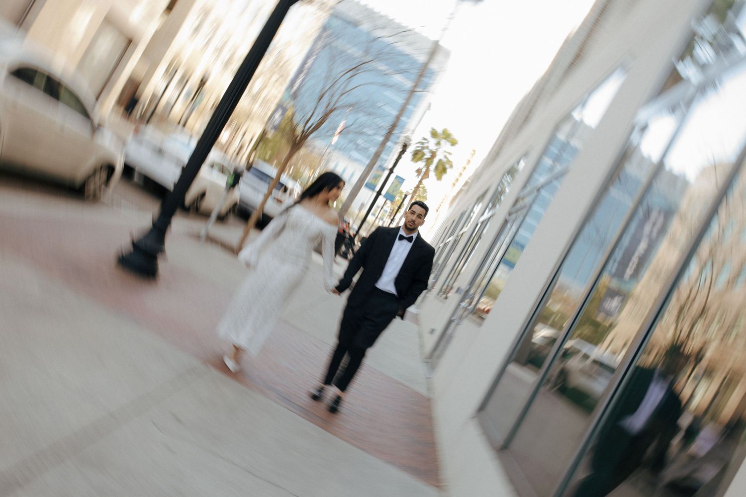 Motion blurred image shows a dark-suited figure walking through a bright modern office corridor with glass walls.