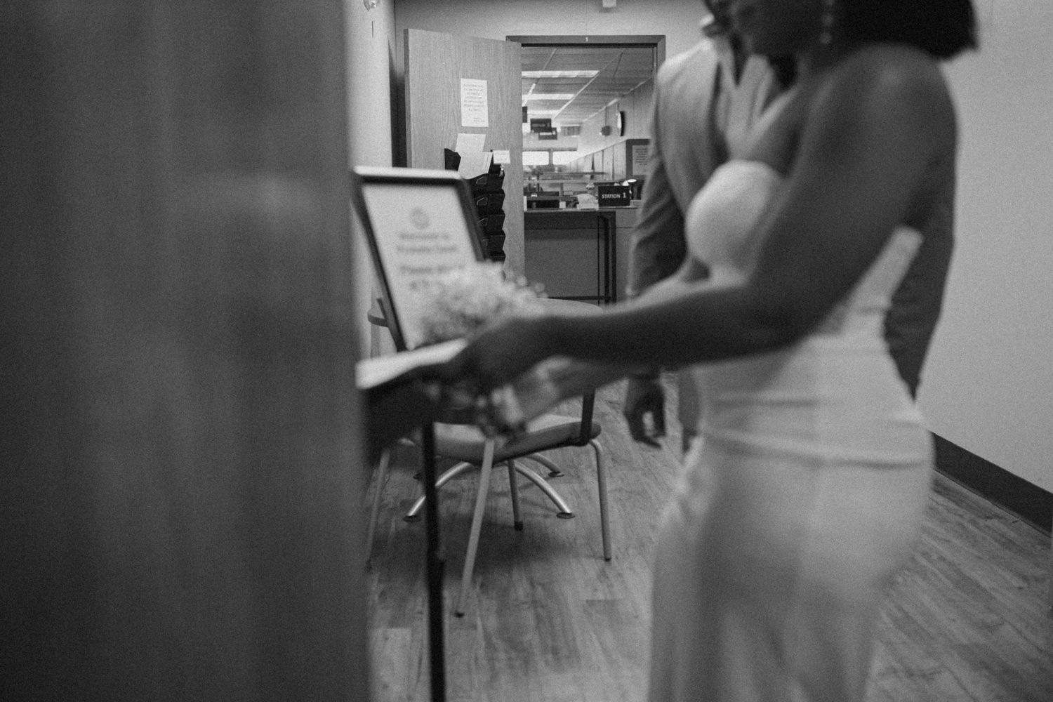 Black and white candid wedding photo in a hallway showing motion and excitement.