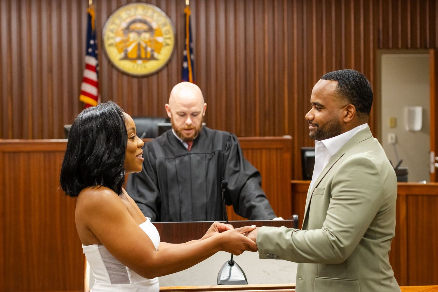 A couple exchanges rings during a civil ceremony in a courthouse with a judge presiding over their intimate wedding.