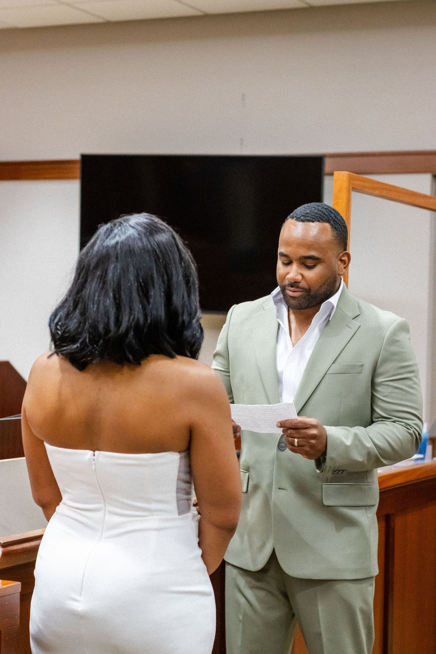 A couple shares an intimate moment during their courthouse wedding ceremony while reading vows together.