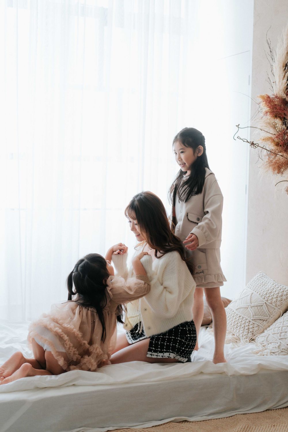 Two people in cozy sweaters share intimate moments while lounging on a bed with white bedding.