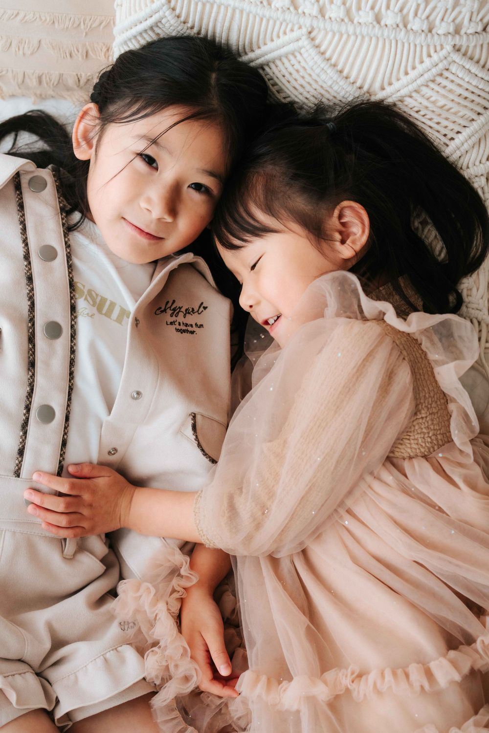 Two people in soft winter clothing share tender moments while lying on white bedding.