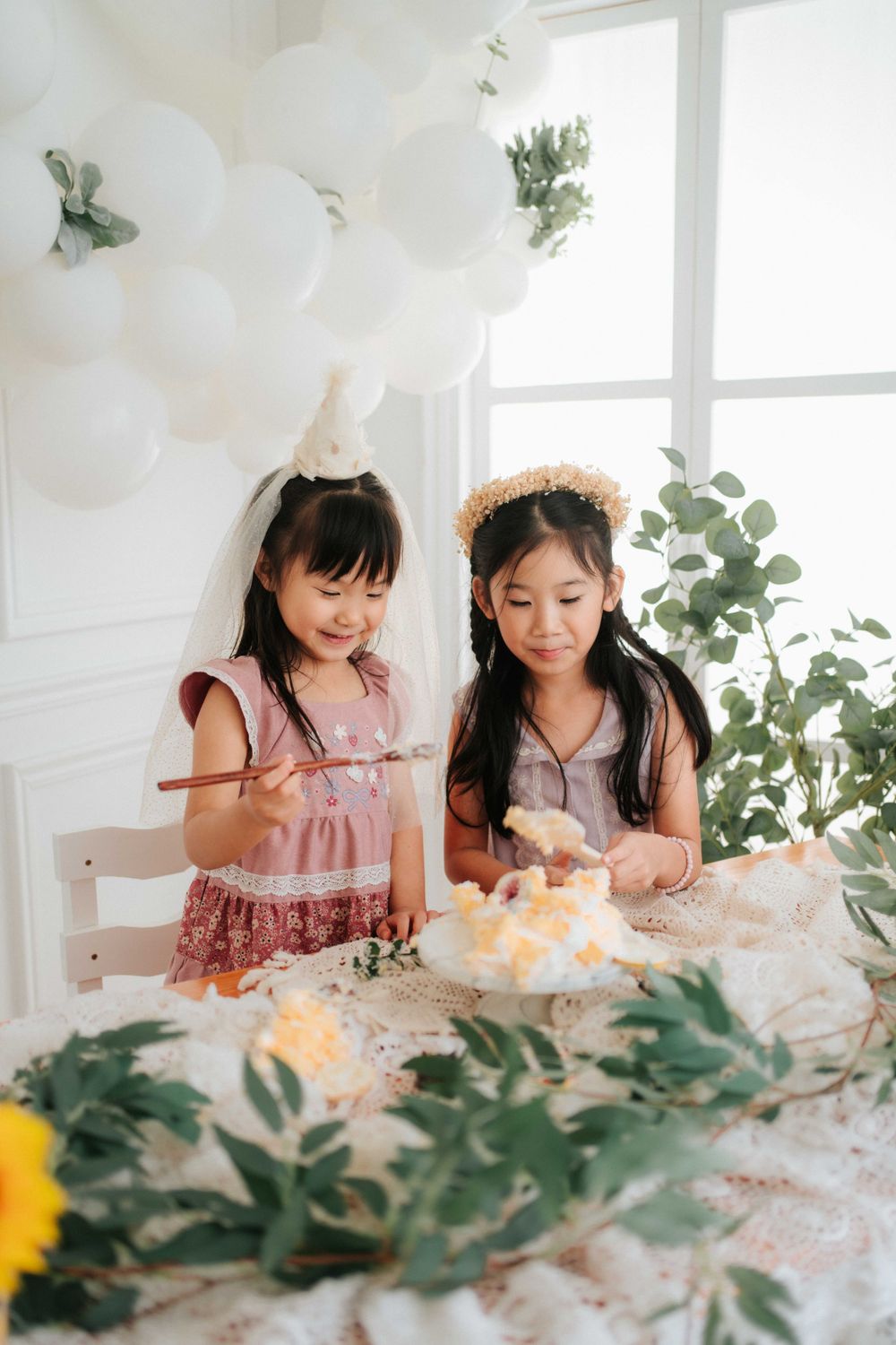 Two people enjoying a celebration with decorative greenery and lighting.