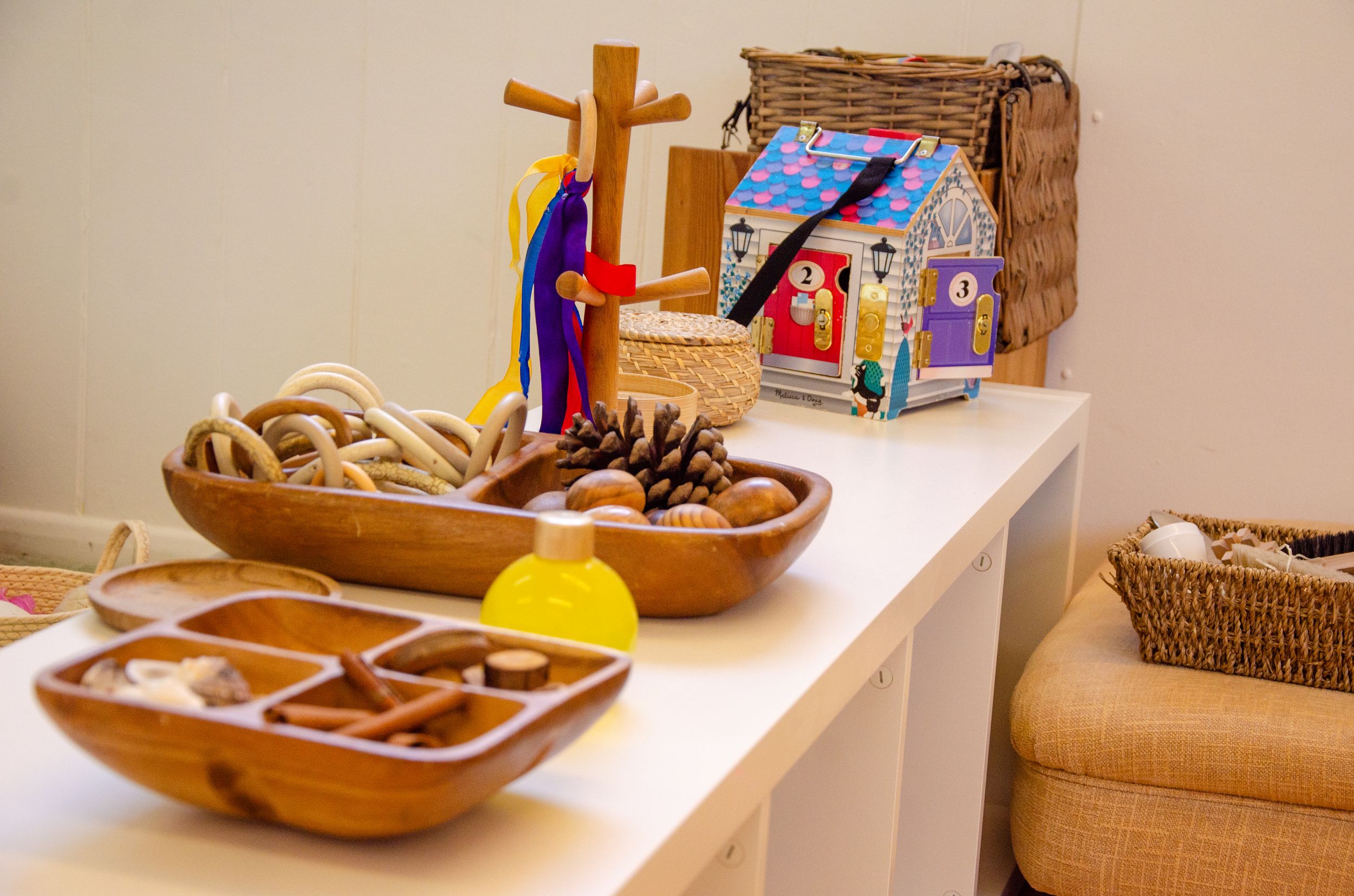 Wooden nativity scene display with decorative bowls on white table.