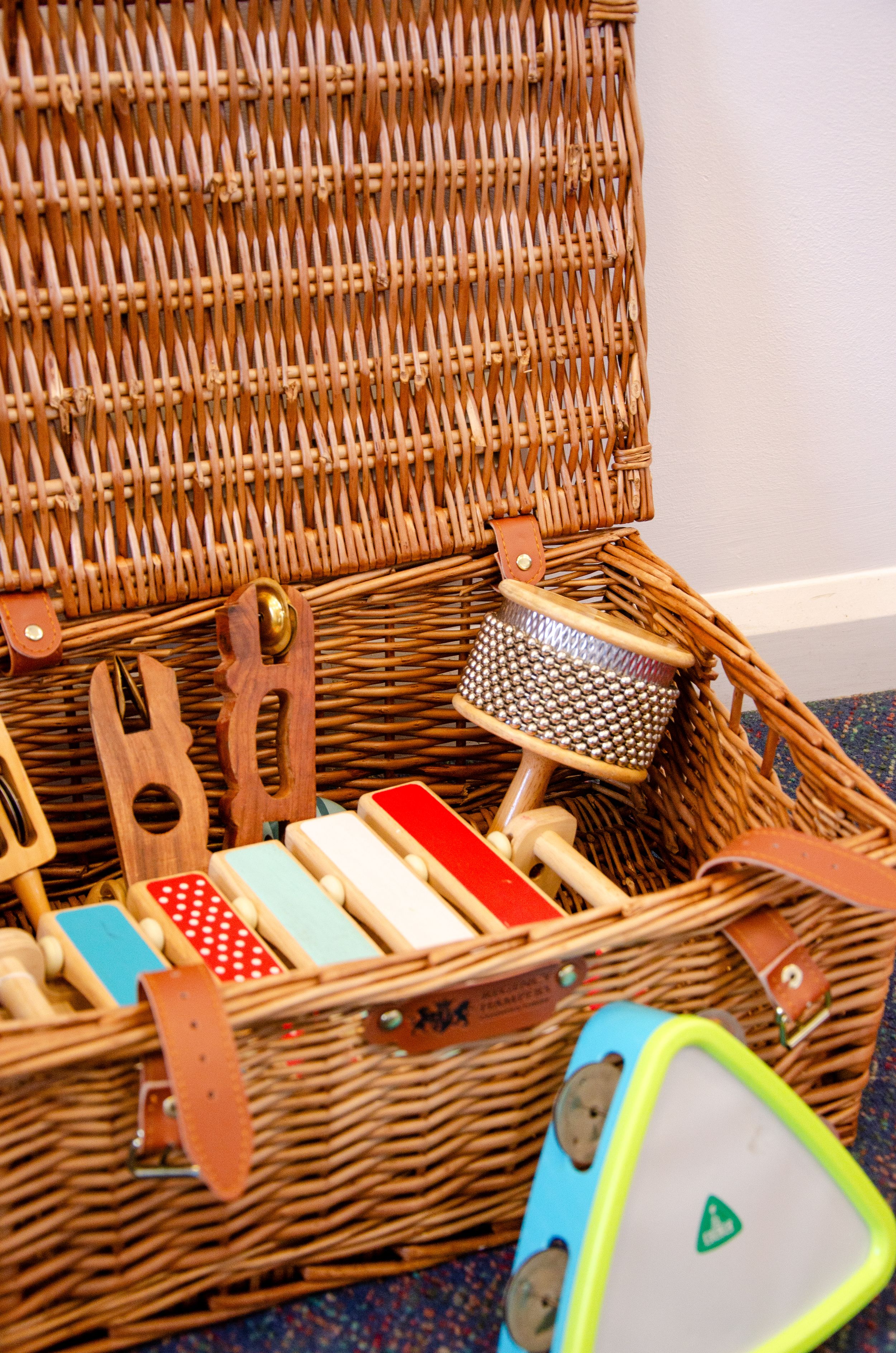 Open wicker basket filled with musical instruments and educational toys.