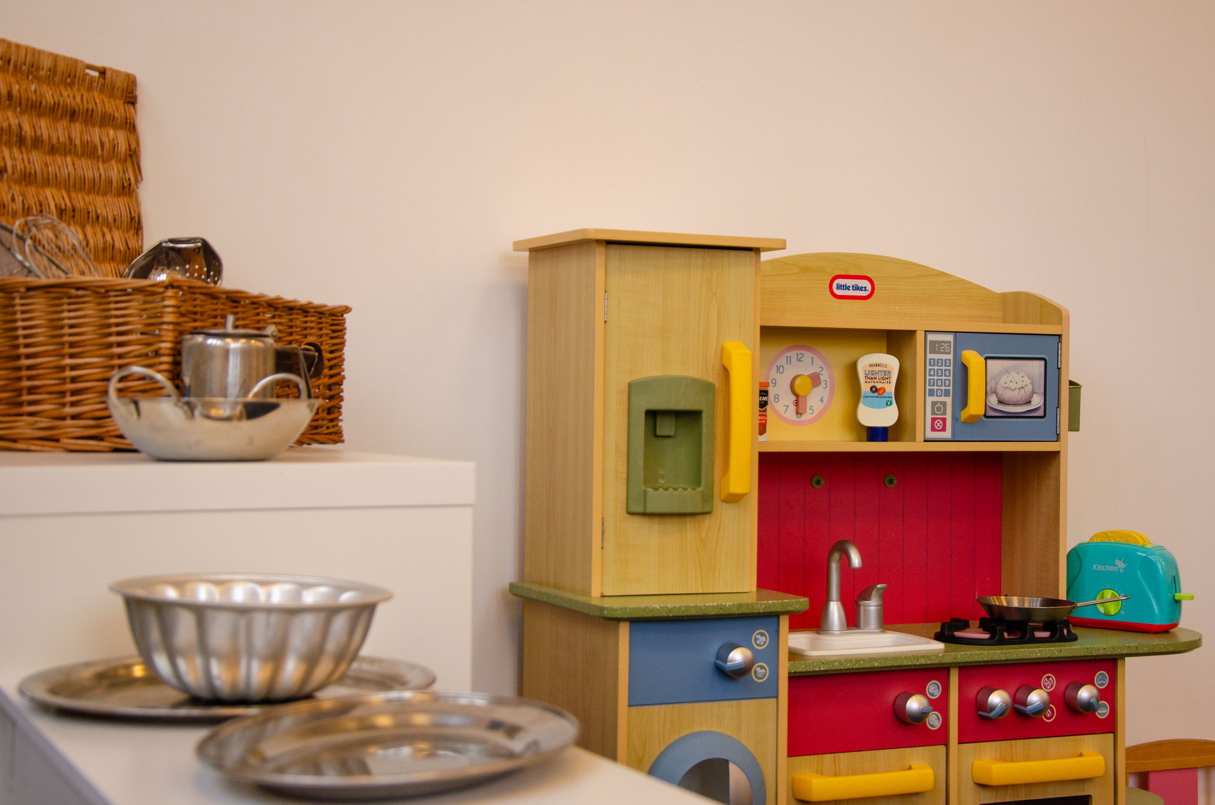 Child-sized play kitchen set with colorful cabinets and pretend appliances.