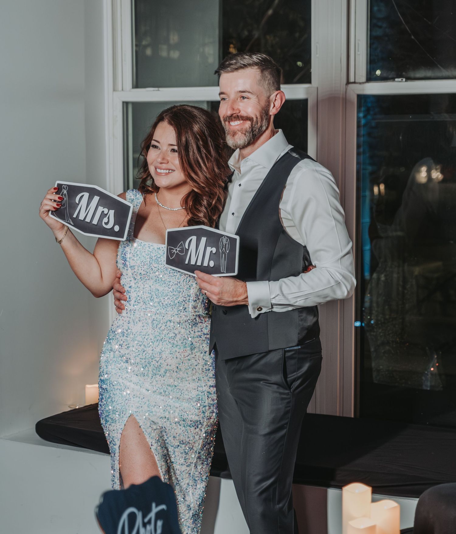 A newly married couple, in formal attire, dancing and laughing together while holding small chalkboard signs at the Halo at the Point venue.