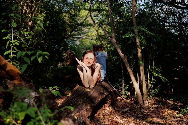 Whimsical forest portrait on fallen tree trunk surrounded by lush greenery.
