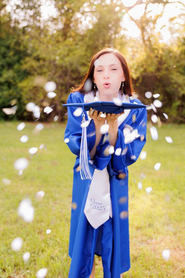 Graduation celebration photo with flying confetti and blue cap and gown.