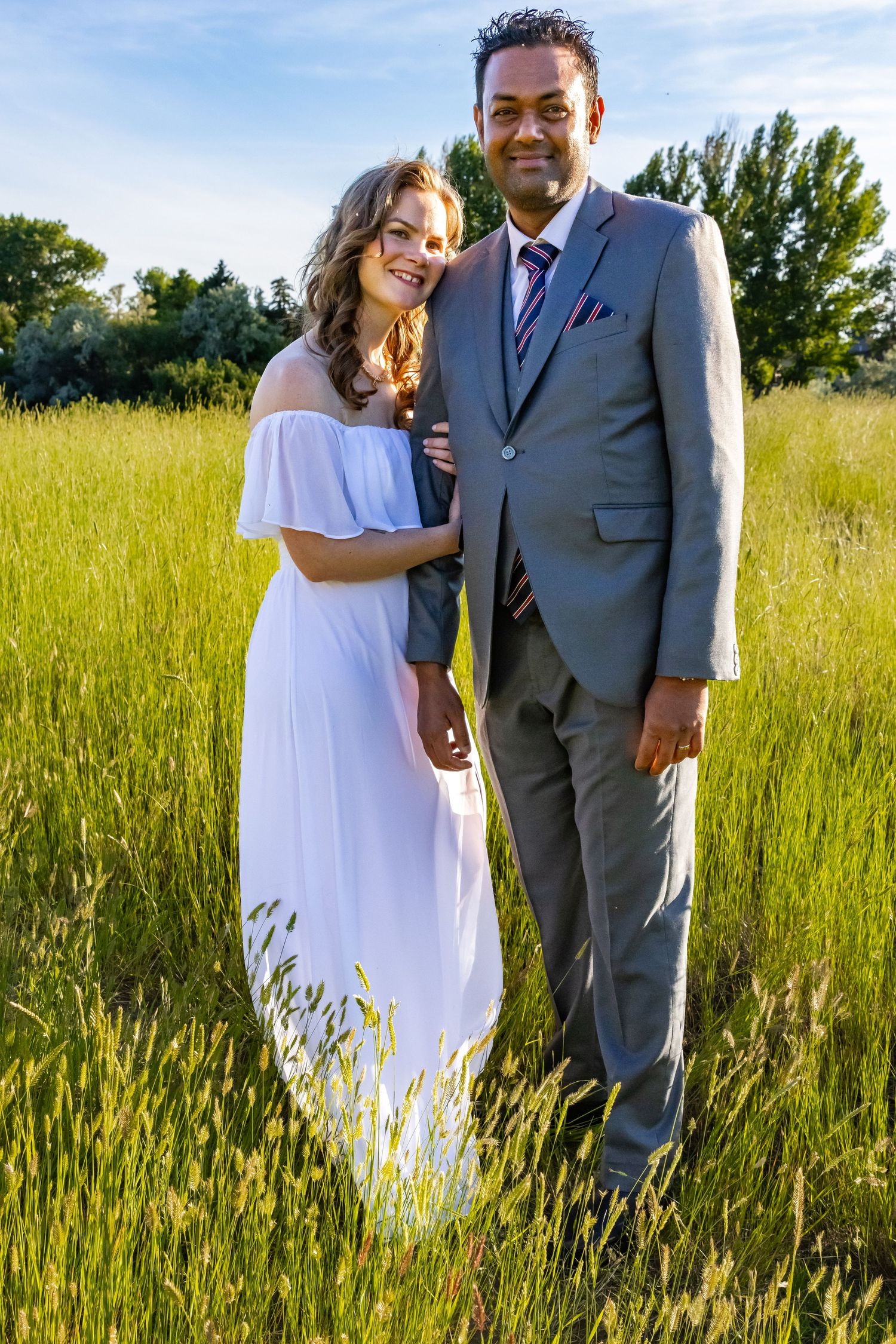 a couple stands in a field.