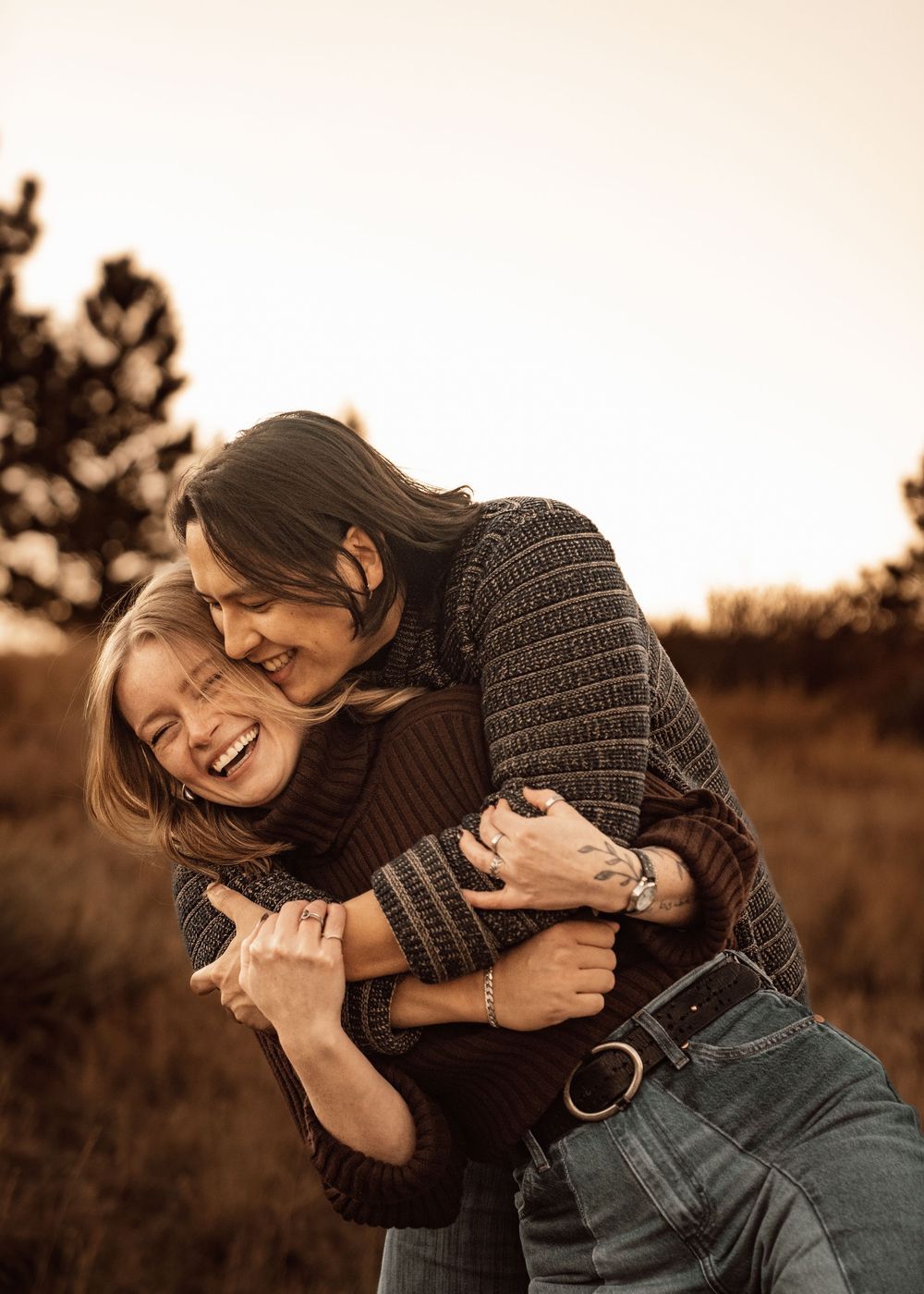 Candid moment of laughter and embraces captured in warm sepia tones during sunset.