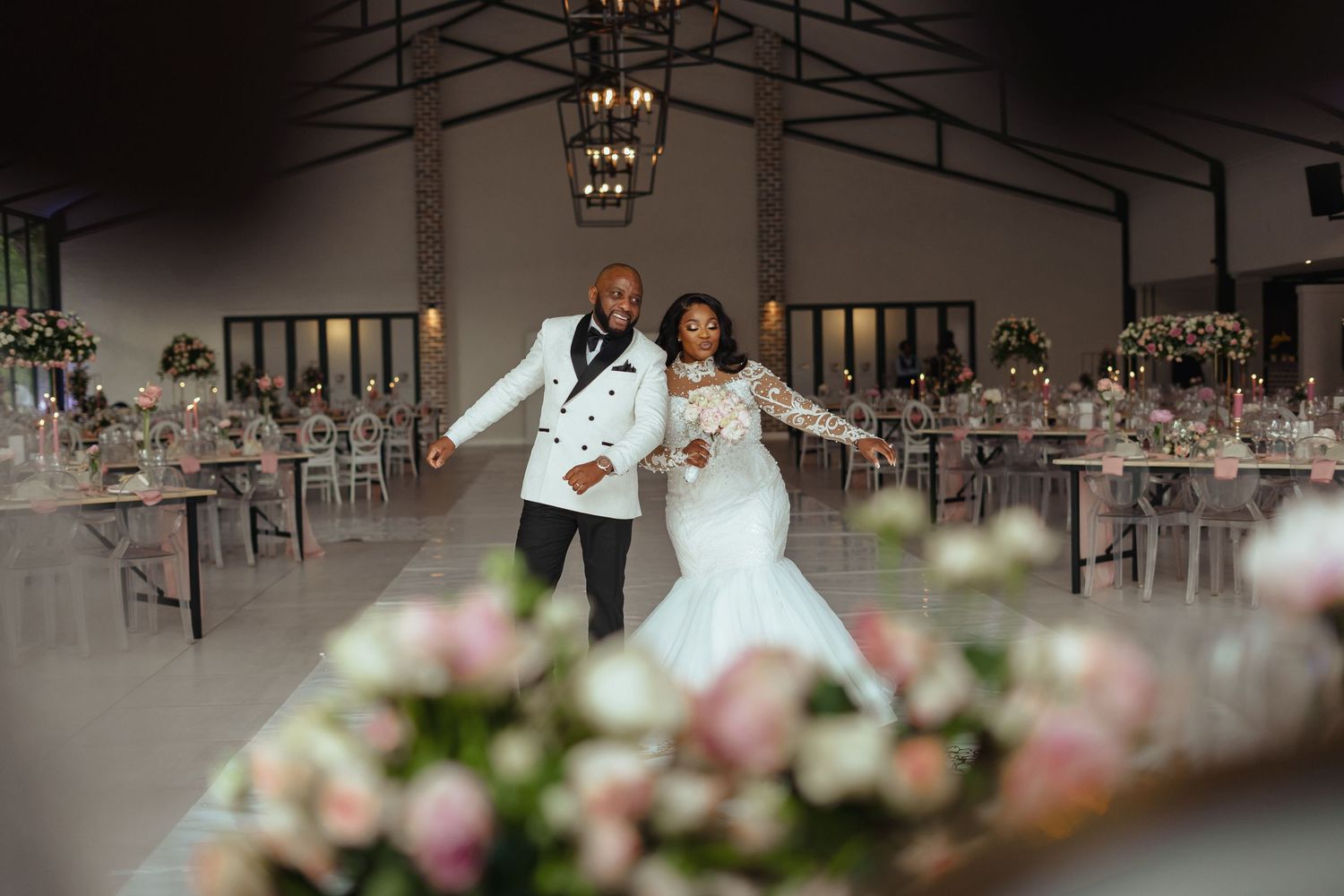 Newlyweds celebrating in a beautifully decorated reception venue with floral centerpieces.