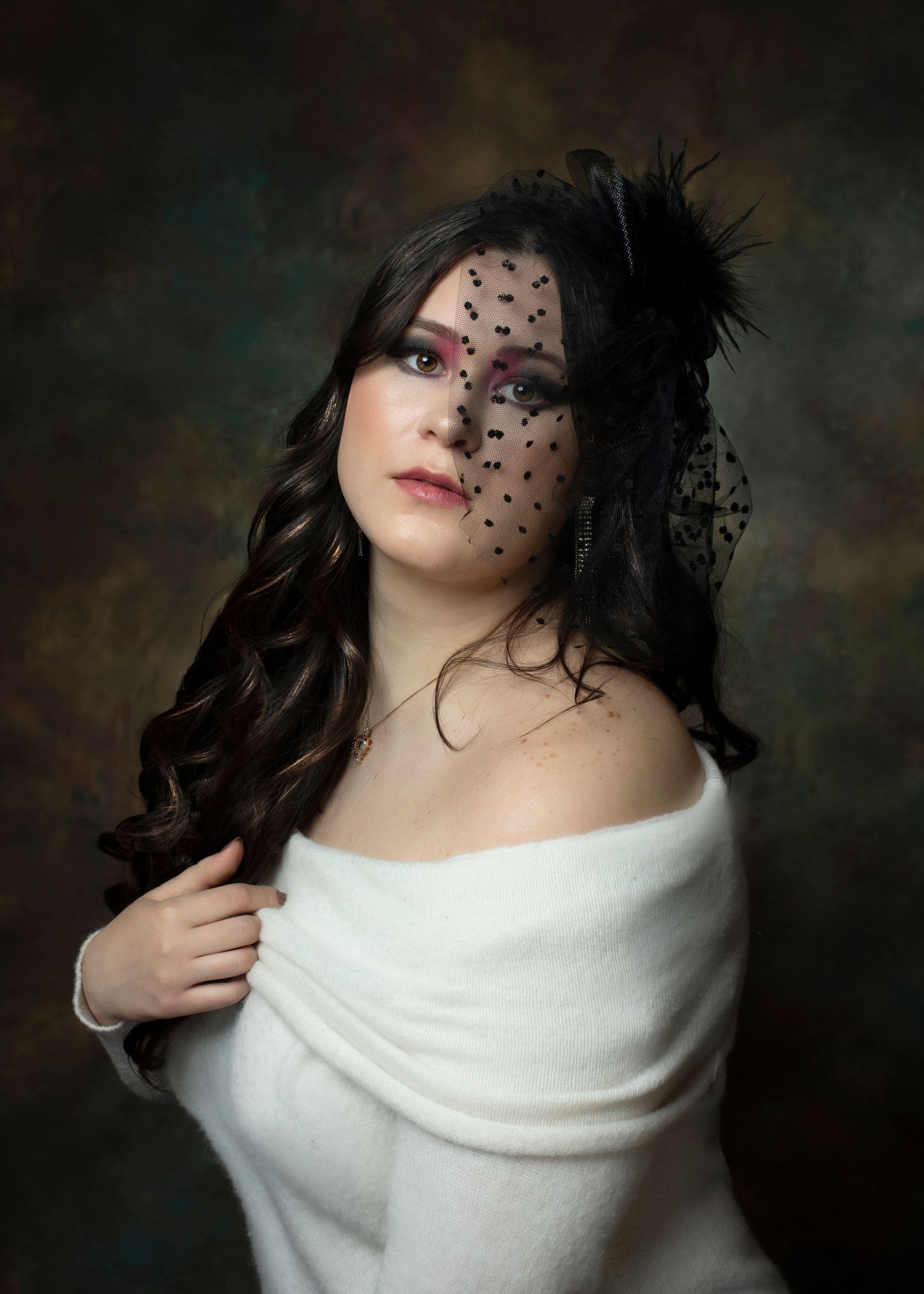 Vintage-inspired portrait with black lace veil and feather fascinator against dark backdrop.