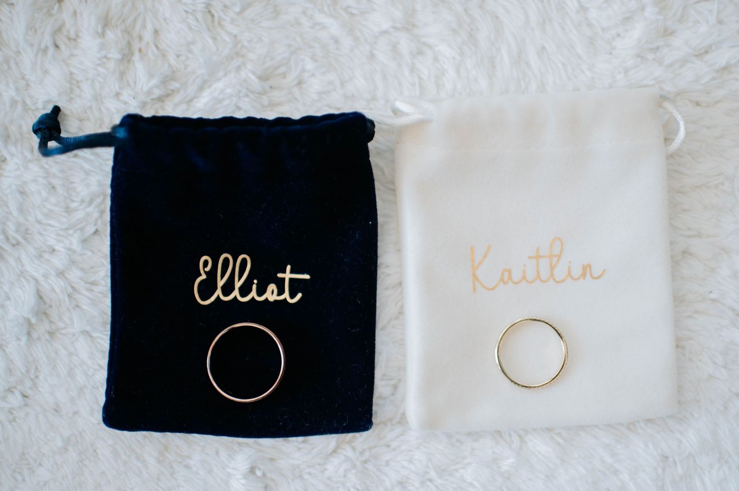 Wedding rings in black and white velvet pouches with gold embroidered text.