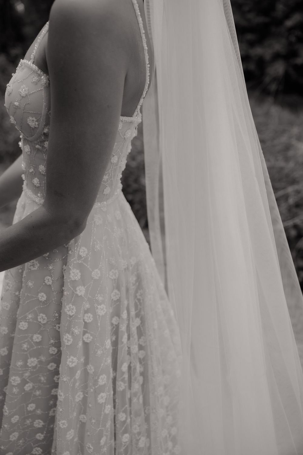 Detailed view of an elegant wedding dress with floral appliques and flowing veil.