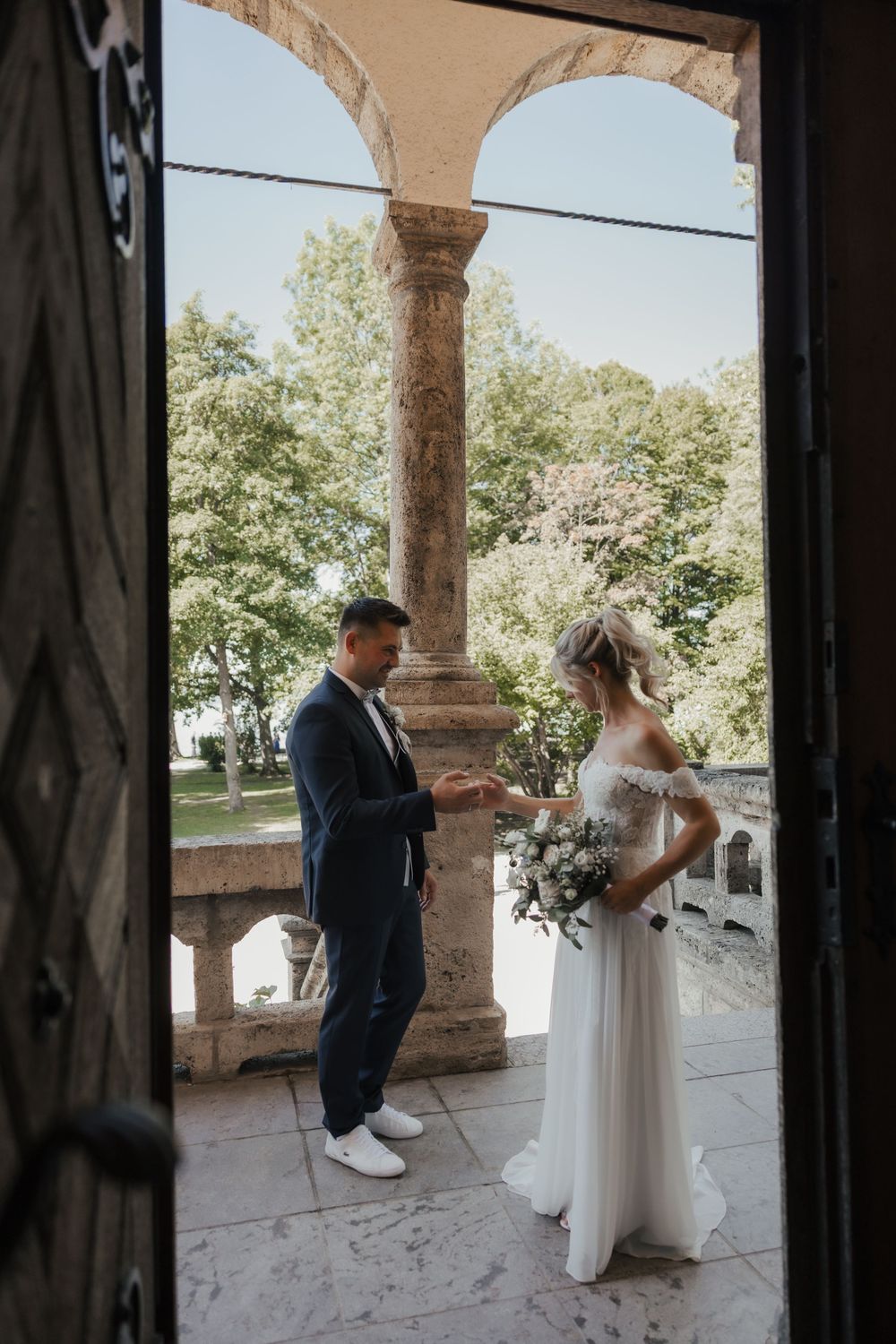 Wedding couple standing under stone archways during an outdoor wedding ceremony.