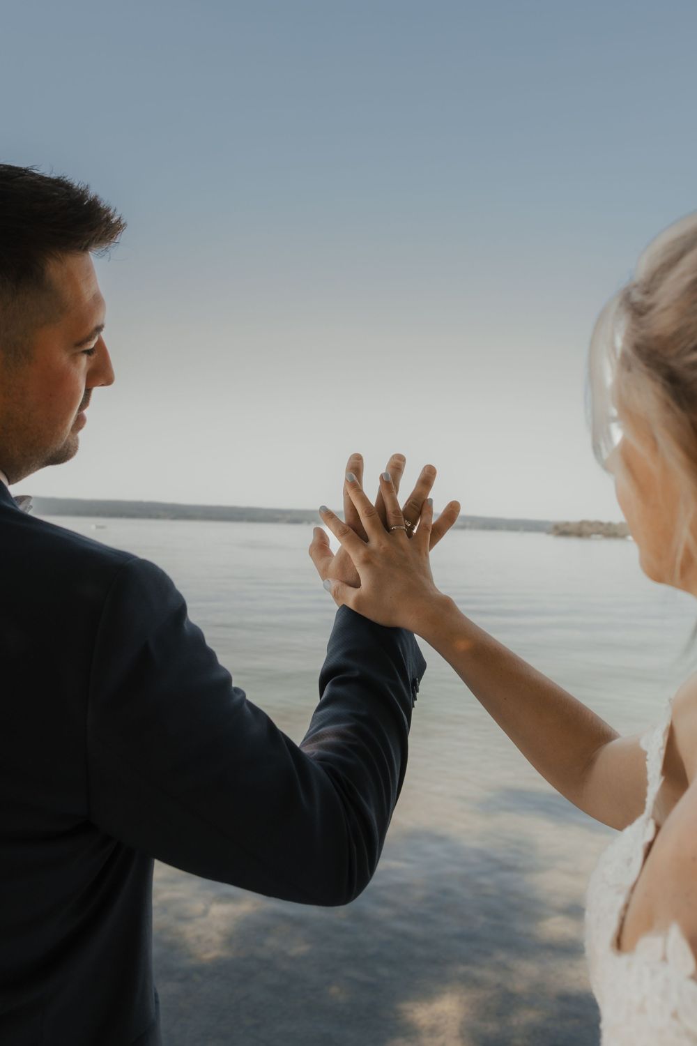 Wedding couple shares playful moment against ocean backdrop during sunset photoshoot.