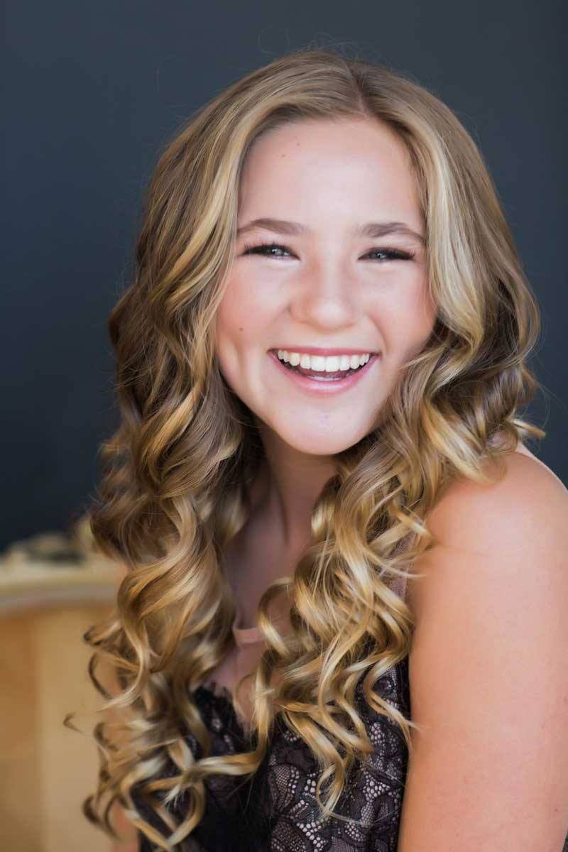 Professional portrait showing a joyful smile against dark background.