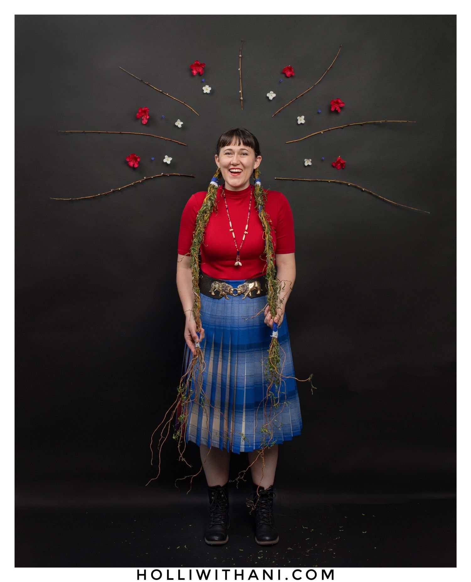 Woman laughing portrait wearing blue skirt and red dress on black background.